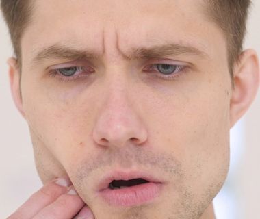 Man holding lower right side of face portraying split tooth pain and a dental emergency