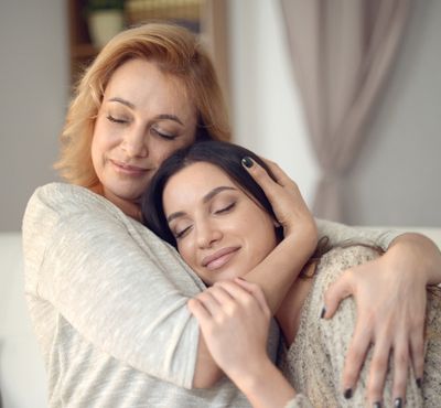 Strawberry blond mom hugging brunett daughter portraying concern for special needs sedation dentistry